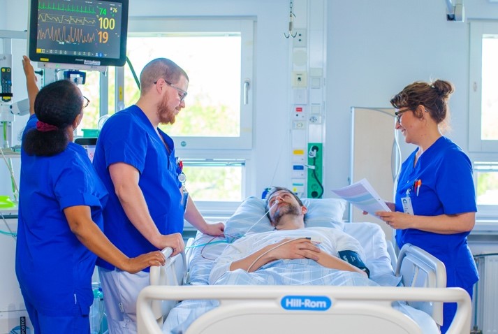 Vårdpersonal pratar med patient i sjukhusmiljö.