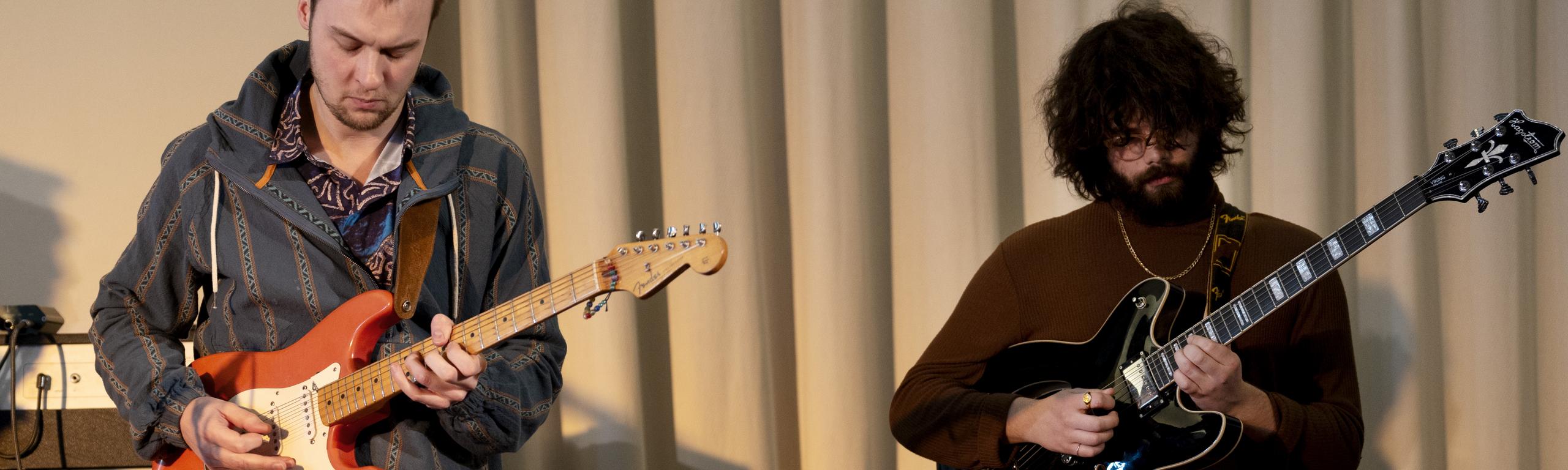 Two persons playing electric guitars
