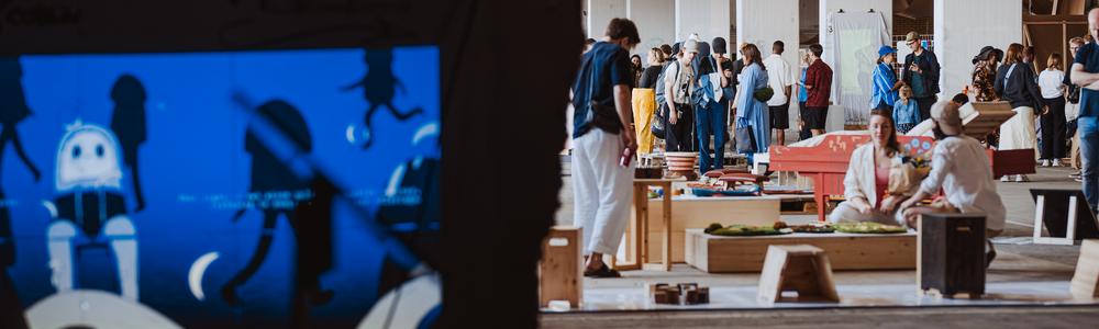 From the inside of a tent, looking out at visitors at the design graduation show 2025.