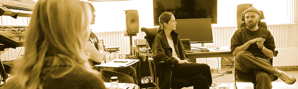 Four people are sitting in a recording studio and having a discussion.