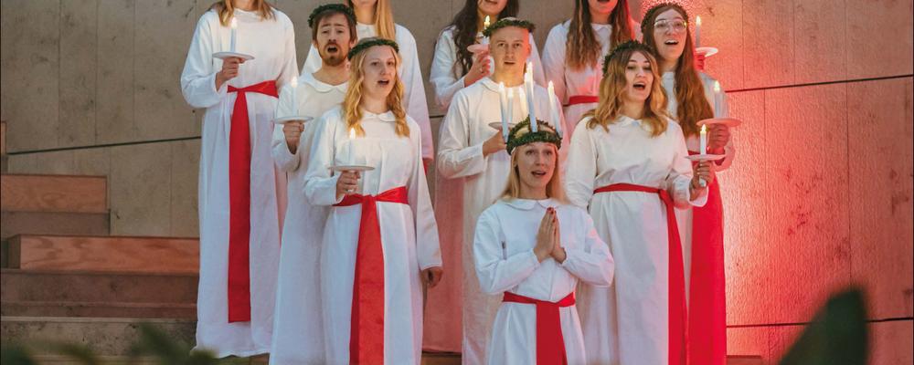 Ett luciatåg med en lucia och nio tärnor i en trappa.