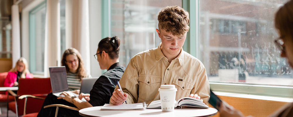 Studenter vid bord i universitetsbiblioteket