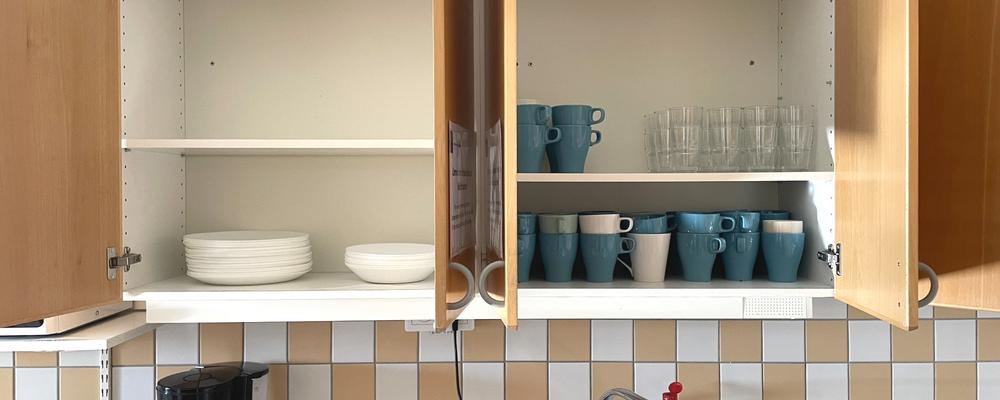 A kitchen cabinet with glasses and mugs