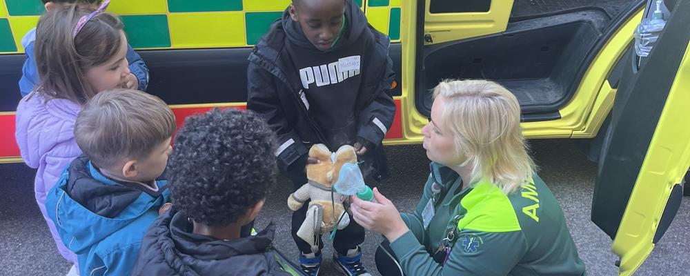 Ambulanssjukvårdare demonstrerar vårdmoment för en grupp barn.