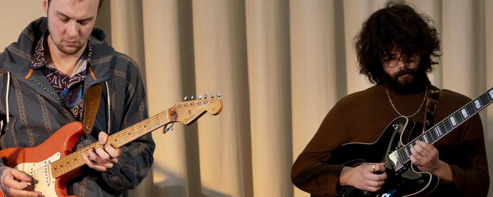 Two persons playing electric guitars