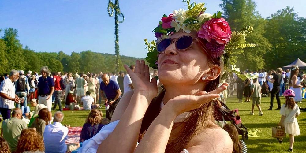 Bild på kvinna framför midsommarfirande.