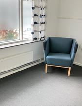en fåtölj står i ett rum med fönster som har insynsskydd