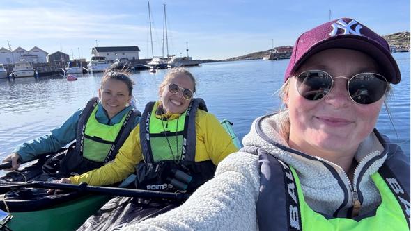 tre kvinnor paddlar kajak i skärgården.