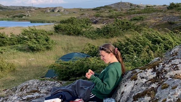 kvinna campar vid havet i vacker skärgårdsmiljö.