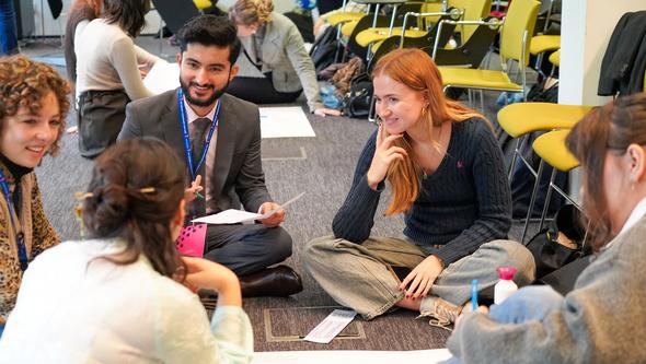 Studenter som sitter på golvet och arbetar